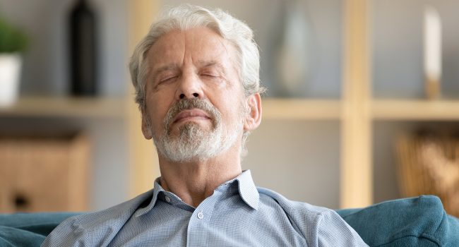 homme d'un certain age, assis dans un fauteuil yeux fermées hypnose
